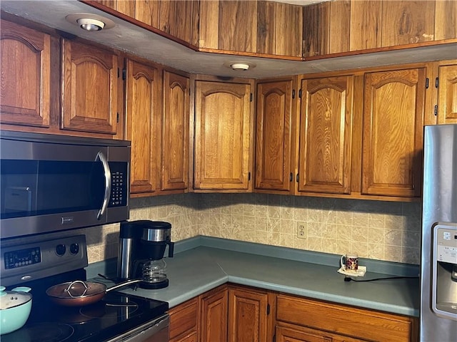 kitchen featuring stainless steel appliances, brown cabinets, tasteful backsplash, and light countertops