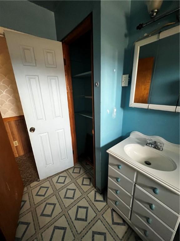 bathroom with vanity, tile patterned floors, a wainscoted wall, and wood walls