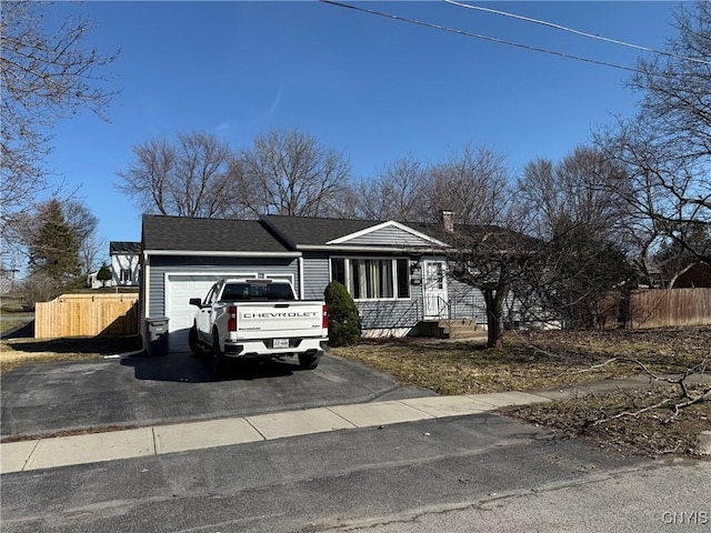 view of front of property featuring aphalt driveway, a garage, a shingled roof, and fence