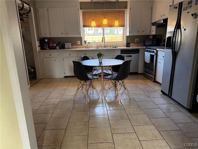 kitchen with under cabinet range hood, stainless steel appliances, white cabinets, light countertops, and light tile patterned floors