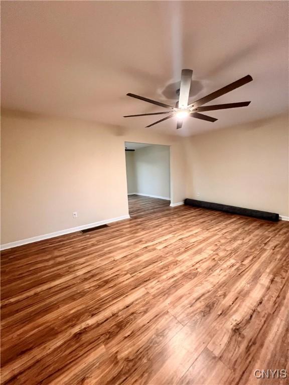 5499 Ravensthorpe, Clay, NY 13041 - unfurnished room featuring wood finished floors, a ceiling fan, and baseboards