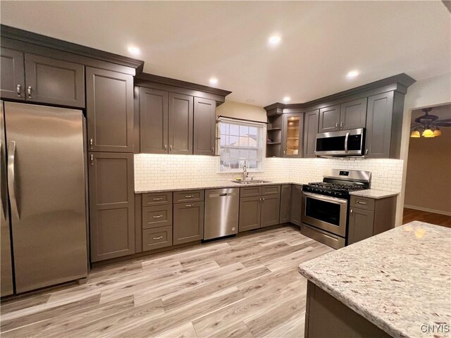 5499 Ravensthorpe, Clay, NY 13041 - kitchen with stainless steel appliances, a sink, light wood-style floors, tasteful backsplash, and light stone counters