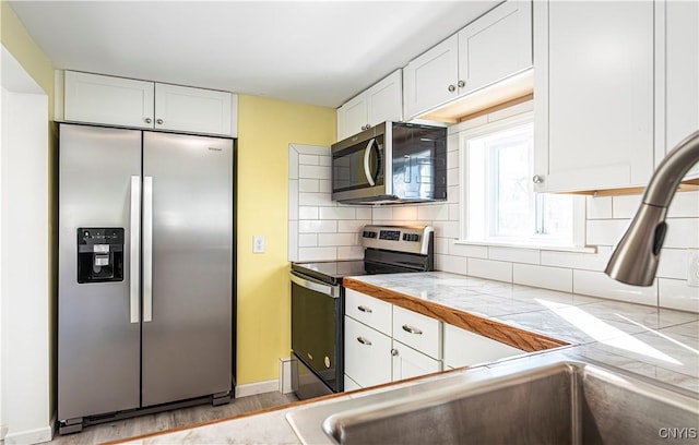 806 Clifford Ave, Vienna, NY 13157 - kitchen featuring tile countertops, stainless steel appliances, backsplash, and white cabinets