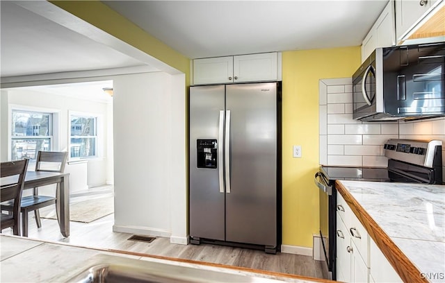 806 Clifford Ave, Vienna, NY 13157 - kitchen featuring light wood-type flooring, backsplash, white cabinetry, stainless steel appliances, and baseboards