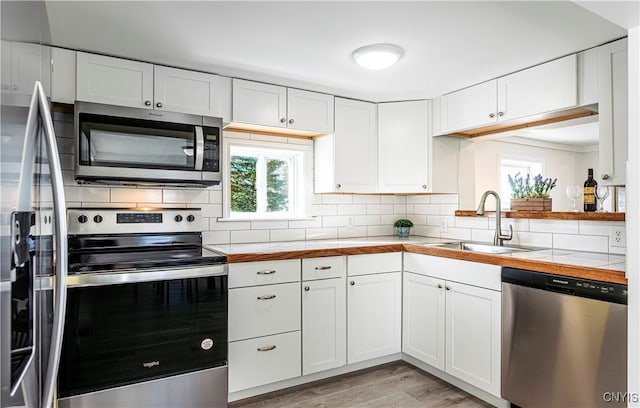 806 Clifford Ave, Vienna, NY 13157 - kitchen with light wood finished floors, backsplash, stainless steel appliances, white cabinetry, and a sink