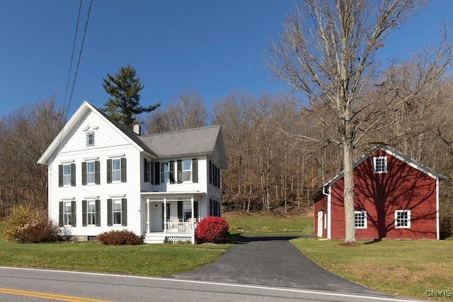 view of front of home with a porch, a front yard, and aphalt driveway
