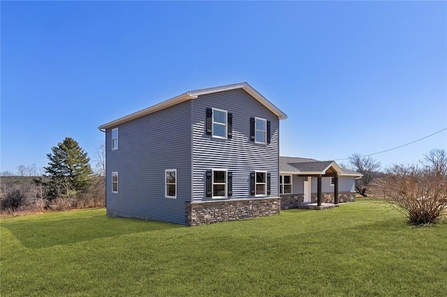 rear view of property with a lawn and stone siding