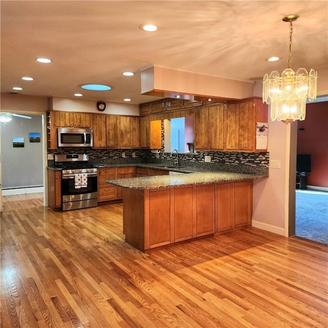 919 W Broad St, Horseheads, NY 14845 - kitchen with brown cabinets, decorative backsplash, appliances with stainless steel finishes, light wood-type flooring, and a peninsula