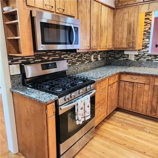 919 W Broad St, Horseheads, NY 14845 - kitchen featuring stainless steel appliances, brown cabinetry, tasteful backsplash, light wood-type flooring, and stone counters