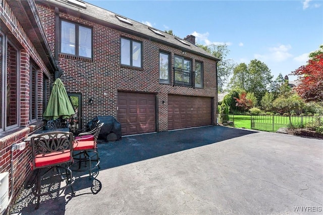 67 Nottingham Ter, Buffalo, NY 14216 - view of front of property featuring brick siding, asphalt driveway, an attached garage, a chimney, and fence
