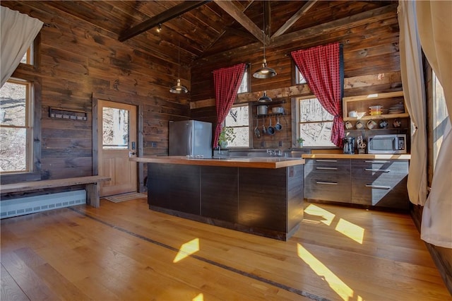 kitchen featuring wood walls, wooden ceiling, beam ceiling, light wood-style flooring, and appliances with stainless steel finishes