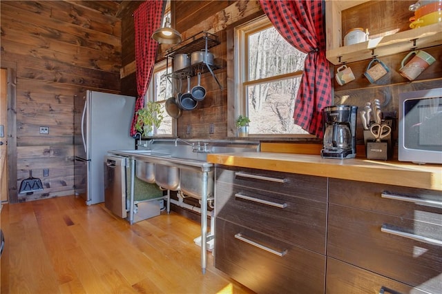 kitchen featuring wooden walls, wood finished floors, and appliances with stainless steel finishes
