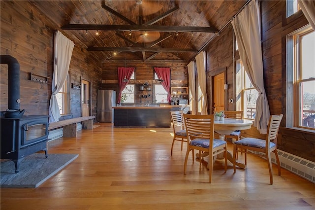 dining room featuring beamed ceiling, wood walls, wood ceiling, and wood-type flooring