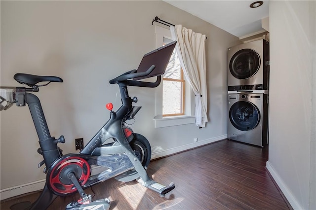 workout room with stacked washer and dryer, dark wood-style flooring, and baseboards