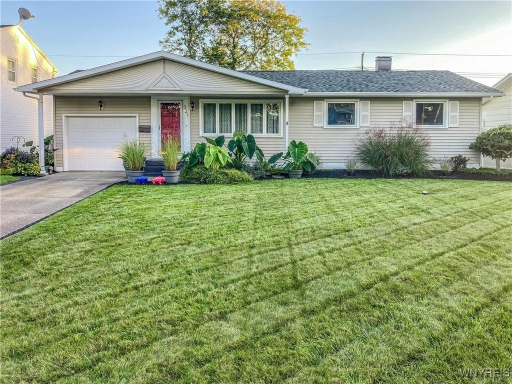 ranch-style home with aphalt driveway, an attached garage, a shingled roof, and a front lawn