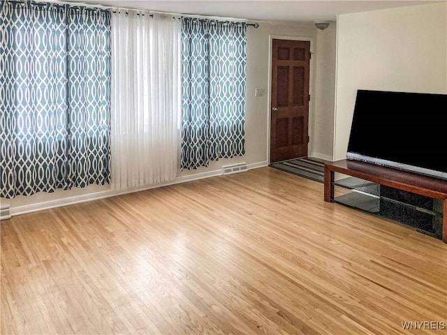 living room featuring visible vents, baseboards, and wood finished floors