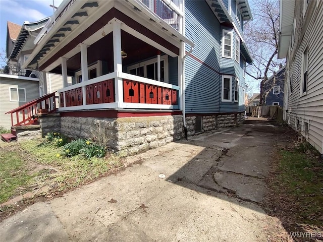 view of side of home with covered porch and concrete driveway