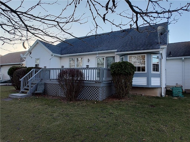 back of house featuring a lawn, roof with shingles, and a wooden deck