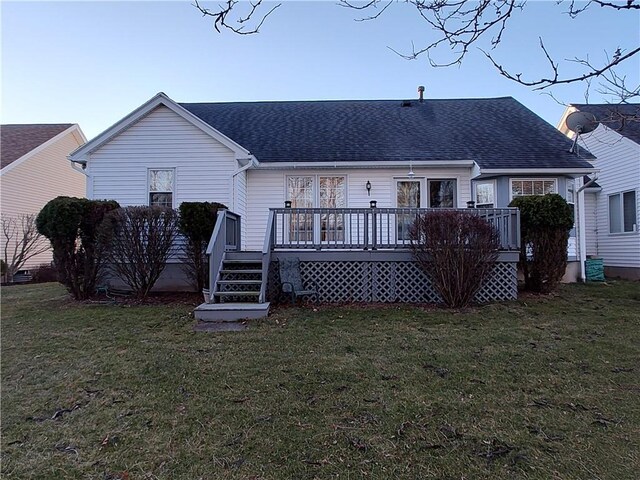 rear view of property with a yard, roof with shingles, and a deck