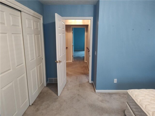 unfurnished bedroom featuring baseboards, a closet, and light carpet