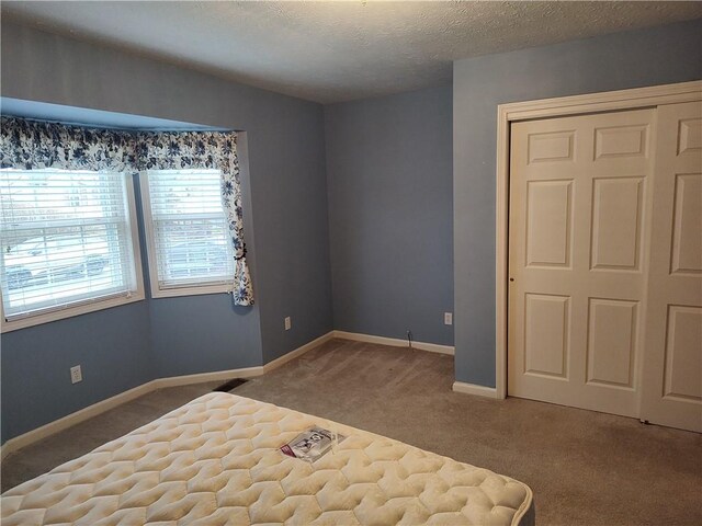 unfurnished bedroom with visible vents, baseboards, a closet, a textured ceiling, and carpet flooring