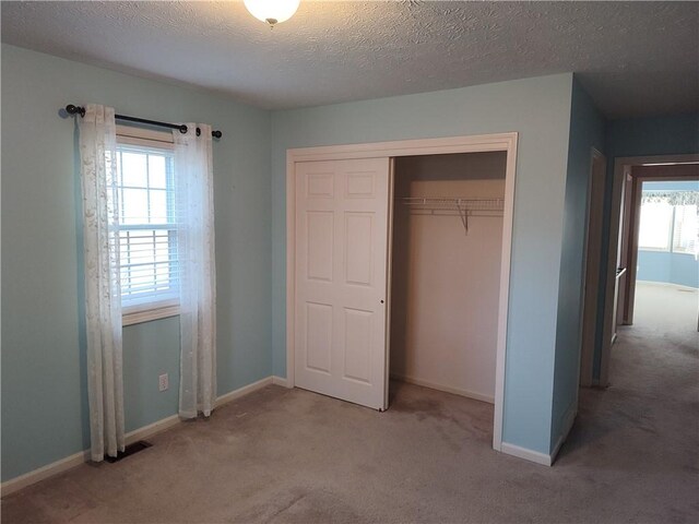 unfurnished bedroom with baseboards, a closet, carpet floors, and a textured ceiling