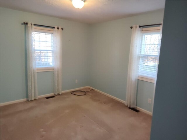 unfurnished room featuring a wealth of natural light, visible vents, and baseboards