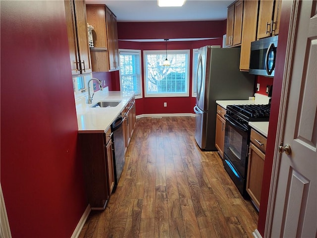 kitchen featuring baseboards, light countertops, dark wood-style floors, black appliances, and a sink