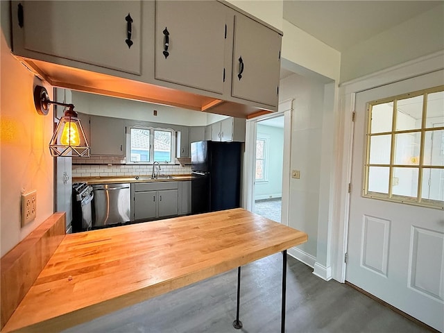 kitchen with black appliances, gray cabinets, a sink, wood counters, and backsplash