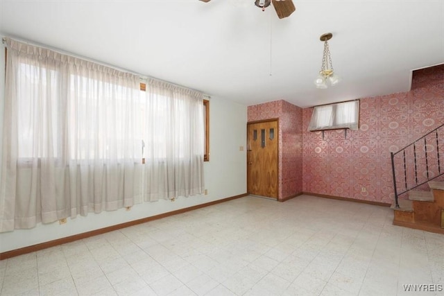 interior space with stairway, baseboards, wallpapered walls, ceiling fan, and tile patterned floors