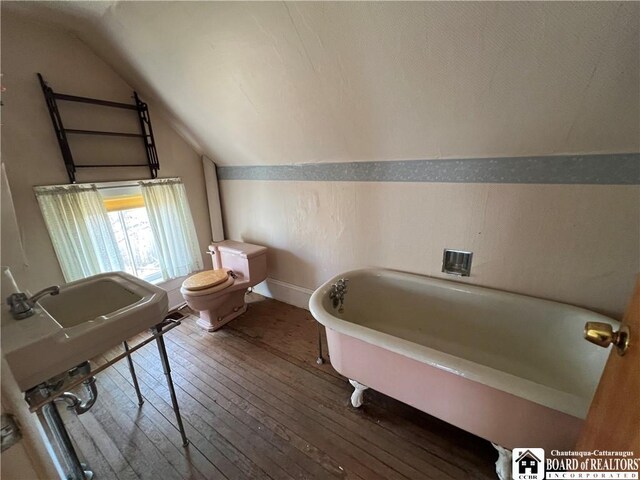 213 S Clinton St, Olean-City, NY 14760 - bathroom featuring hardwood / wood-style floors, baseboards, a freestanding bath, vaulted ceiling, and toilet