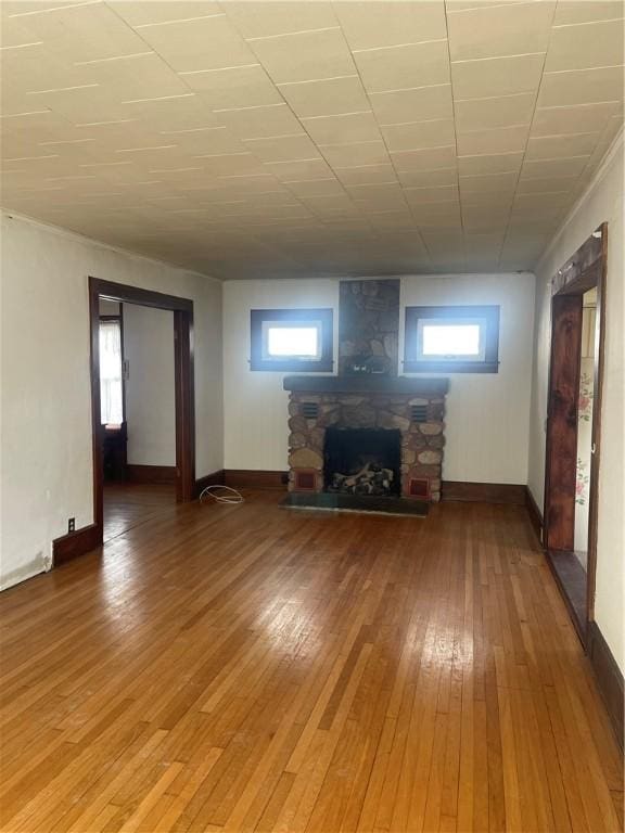 unfurnished living room featuring a fireplace, light wood-style flooring, baseboards, and plenty of natural light