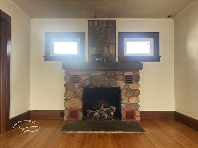 detailed view of crown molding, baseboards, wood finished floors, and a fireplace