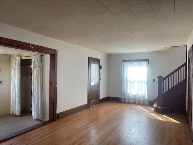 foyer with stairway, wood finished floors, baseboards, and ornamental molding