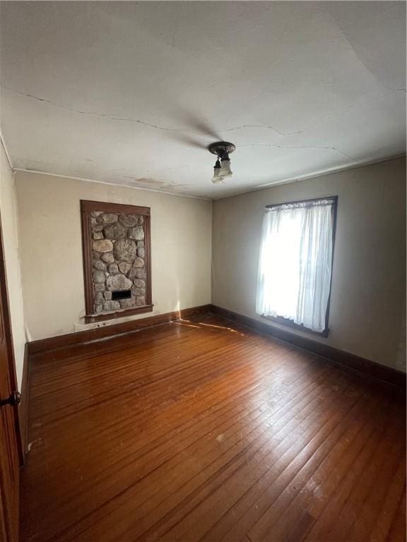 unfurnished living room featuring baseboards, hardwood / wood-style flooring, and a fireplace