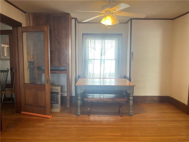 dining room with a ceiling fan, ornamental molding, light wood-style flooring, heating unit, and baseboards