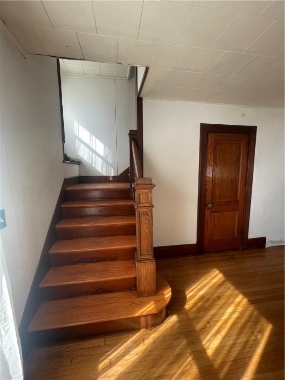 stairway featuring wood finished floors and baseboards