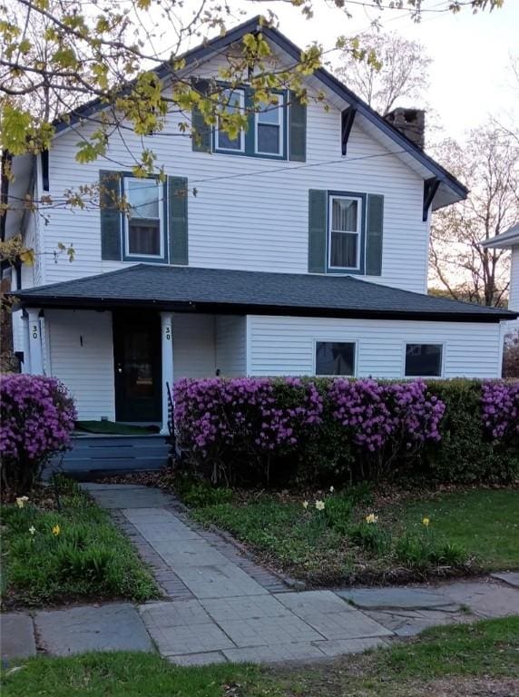 view of front facade featuring a chimney and a porch