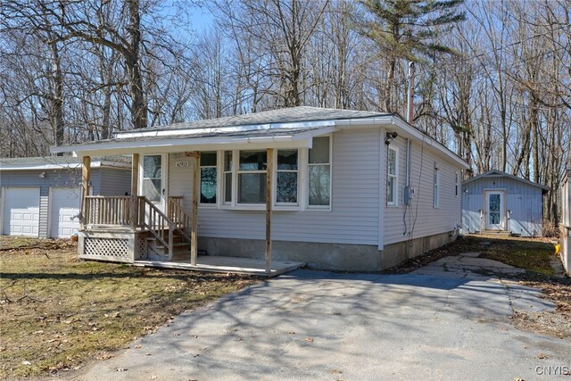 view of front of property with a garage, covered porch, and an outdoor structure