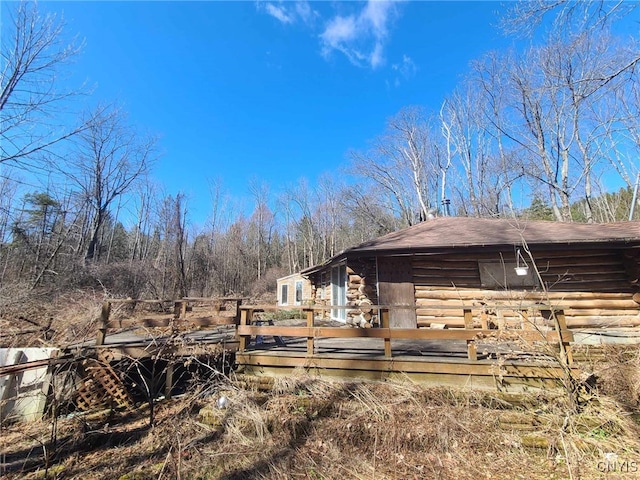 exterior space featuring a deck, log exterior, and roof with shingles