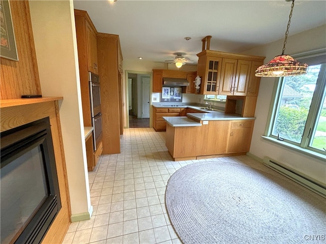 kitchen featuring glass insert cabinets, a baseboard heating unit, wall chimney range hood, light countertops, and a peninsula