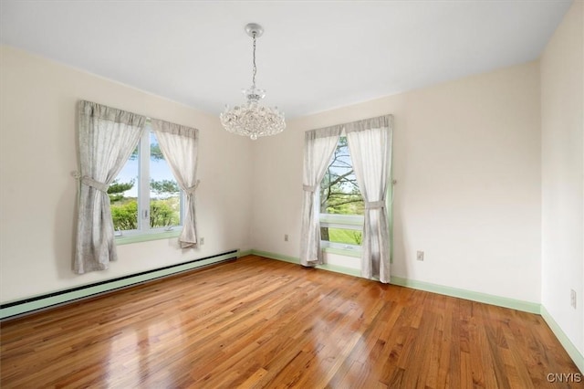 empty room featuring light wood-style flooring, a notable chandelier, baseboards, and a baseboard radiator