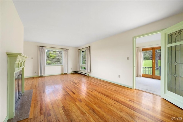 unfurnished living room with a premium fireplace, wood finished floors, baseboards, and a baseboard radiator