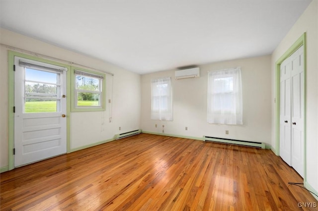 interior space with a baseboard heating unit, light wood-style flooring, and a wall mounted AC
