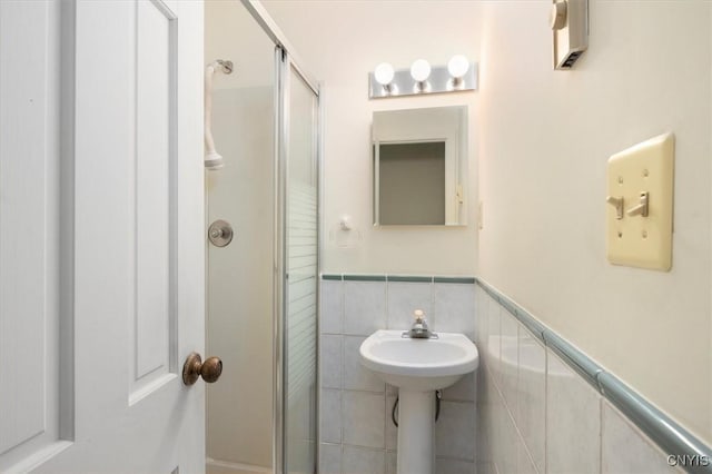 bathroom with tile walls, a stall shower, and wainscoting