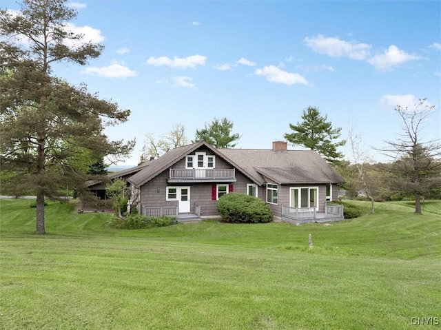 view of front of property with a chimney, a front yard, and a shingled roof