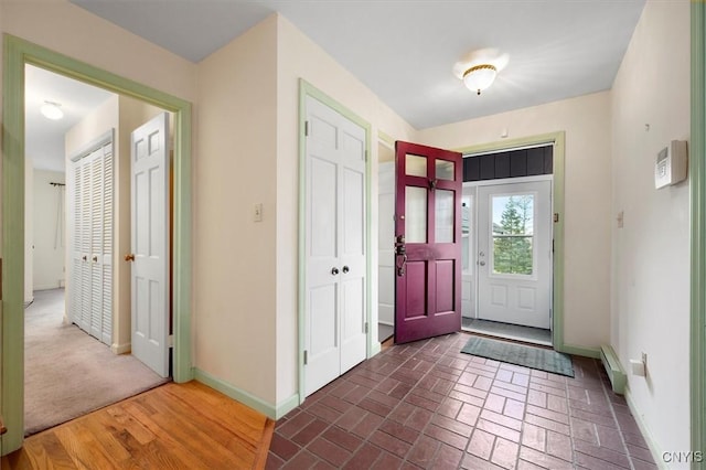 entryway with baseboard heating, brick floor, and baseboards