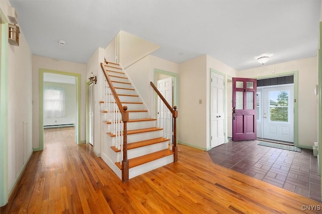 entryway with baseboard heating, stairs, baseboards, and wood finished floors