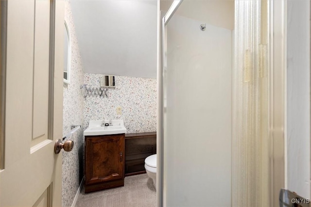 bathroom with a shower stall, toilet, wallpapered walls, and vanity