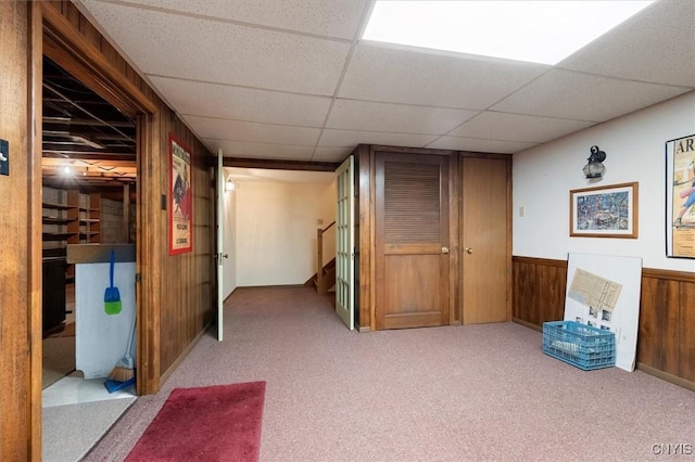 finished below grade area with a wainscoted wall, wood walls, a paneled ceiling, and carpet floors